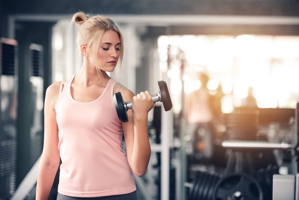 young-woman-exercising-with-dumbbells-in-gym-royalty-free-image-1595935406